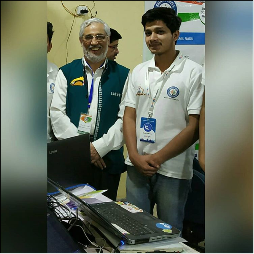 Ali Mustufa Shaikh stands beside the AICTE Chairman at Smart India Hackathon 2018, with laptops and equipment on the table in front of them.